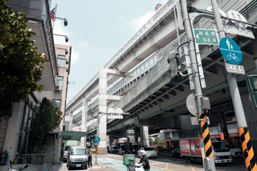 Dynamic urban landscape in New Taipei City showing elevated roads, traffic, and pedestrians.